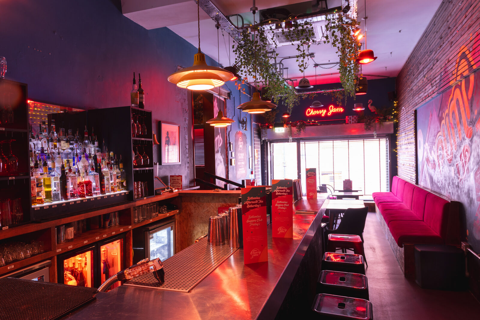 The bar at Cherry Jam — red lighting, hanging plants, Cherry Jam neon sign