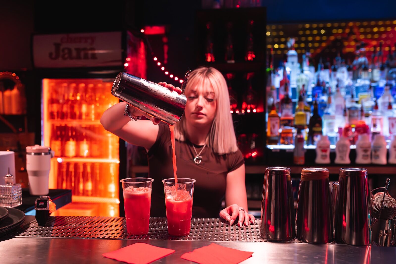 A bartender at Cherry Jam pouring a fresh cocktail at the back bar